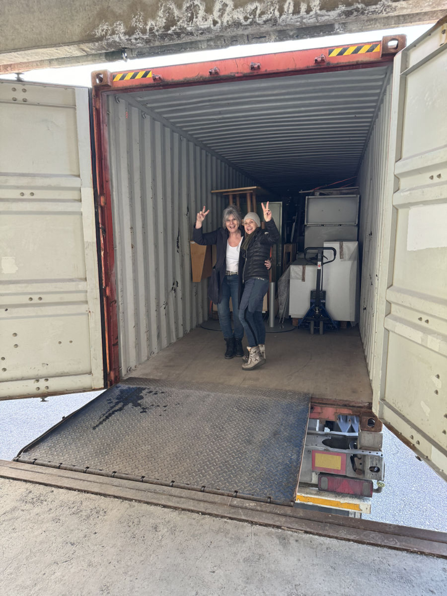 Zwei Frauen blicken lächelnd in die Kamera beim Beladen des Containers in Innsbruck.