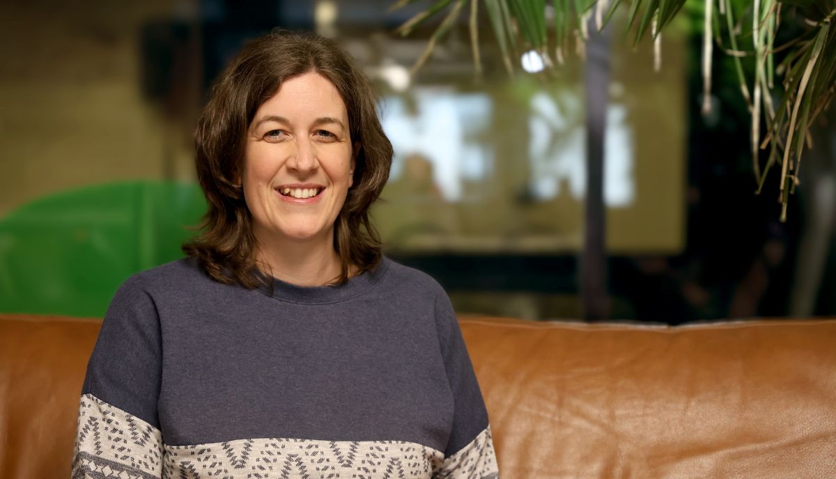 Corinne Fürhapter sitzt auf einer Couch und lächelt in die Kamera